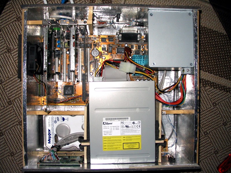 Der Blick von oben in das offene Gehäuse offenbar das Mainboard (links oben), inklusive diverser PCI-Steckkarten, die Festplatte (links unten), das DVD-ROM (unten mitte) sowie das ATX-Netzteil (rechts oben).